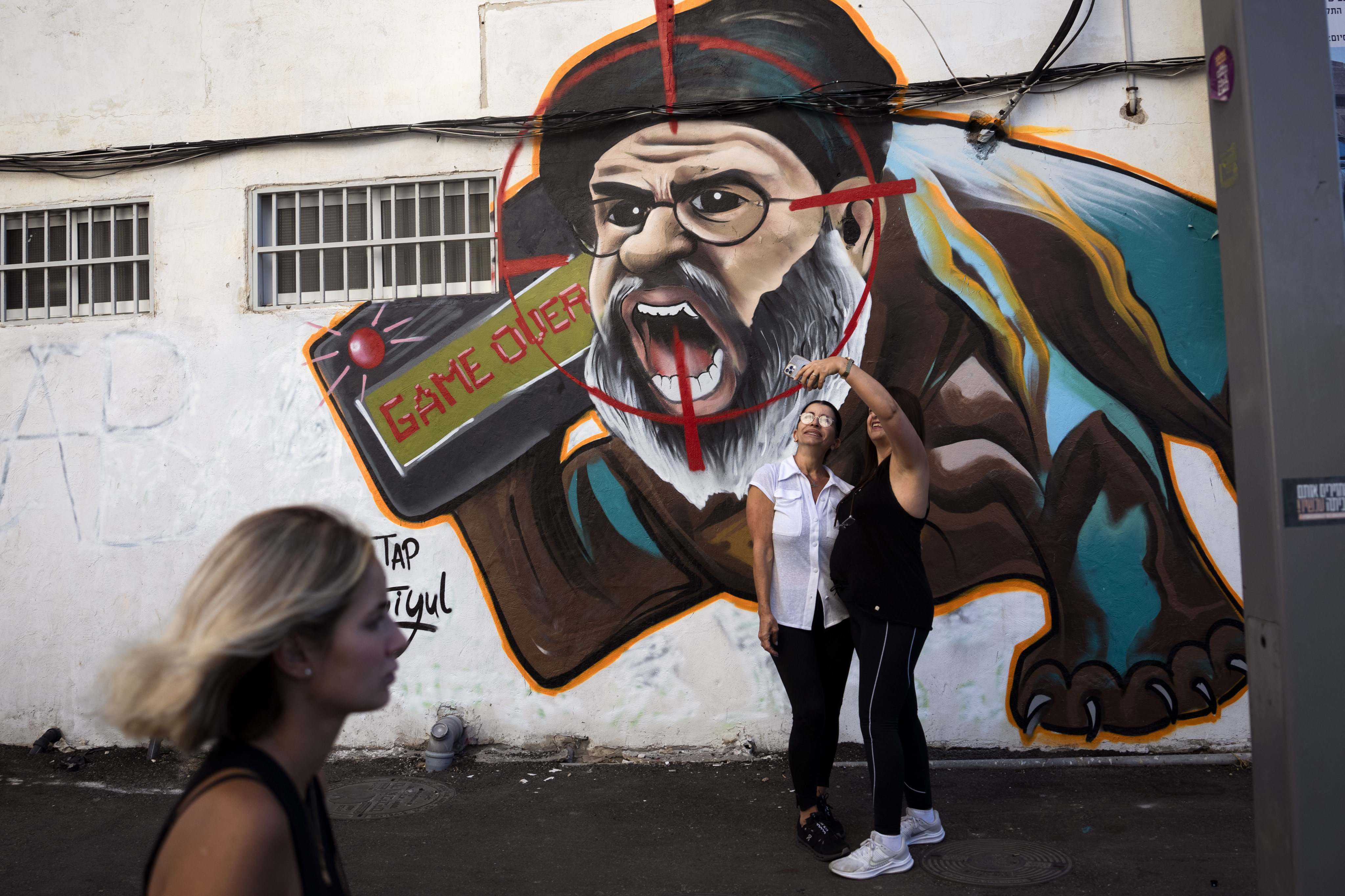 Two women take a selfie next to a newly painted graffiti of slain Hezbollah leader Hassan Nasrallah in Tel Aviv, Israel, in September. Photo: AP