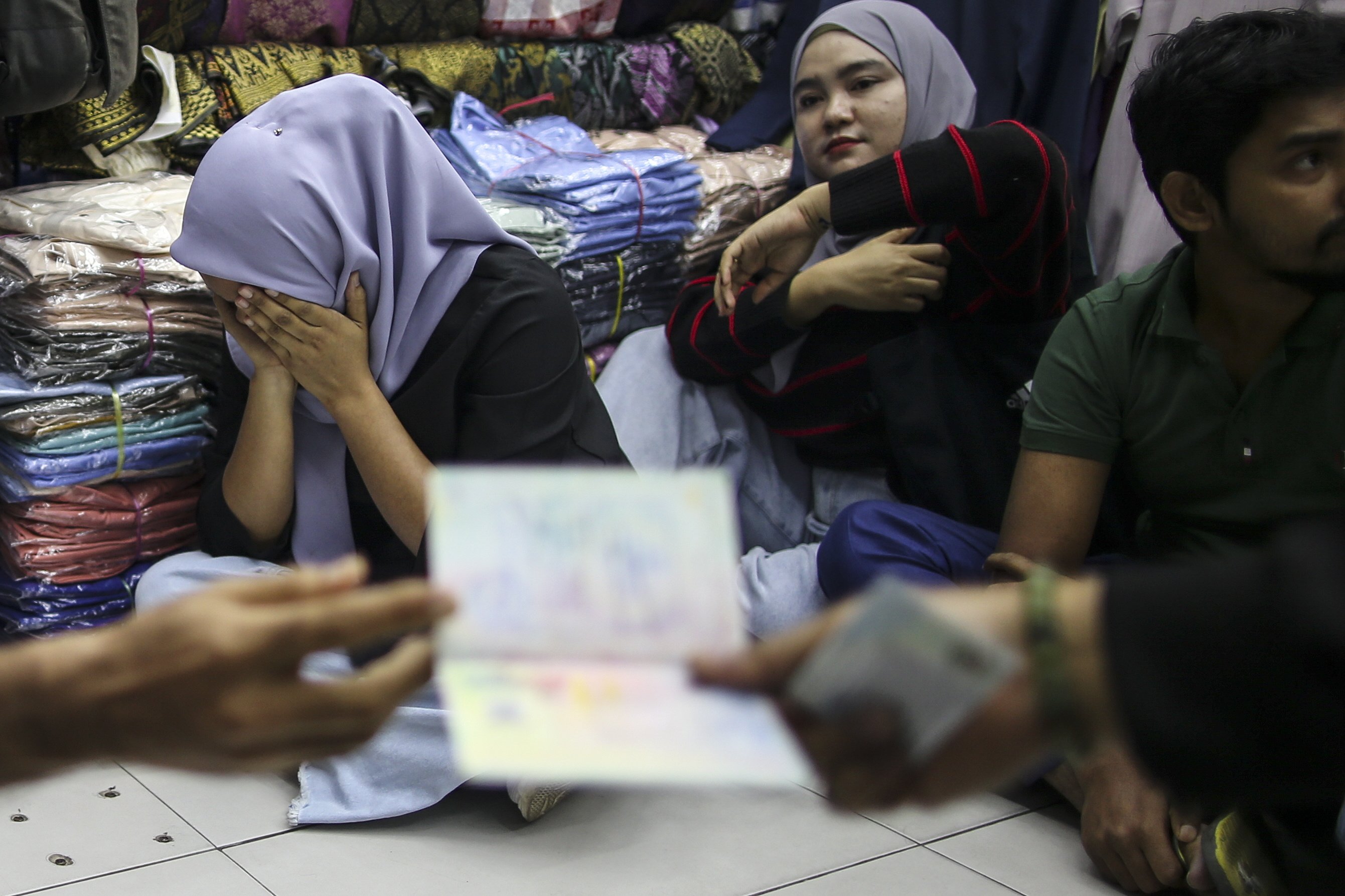 Detainees react during an immigration raid at a clothing store Malaysia on August 15. Photo: EPA-EFE