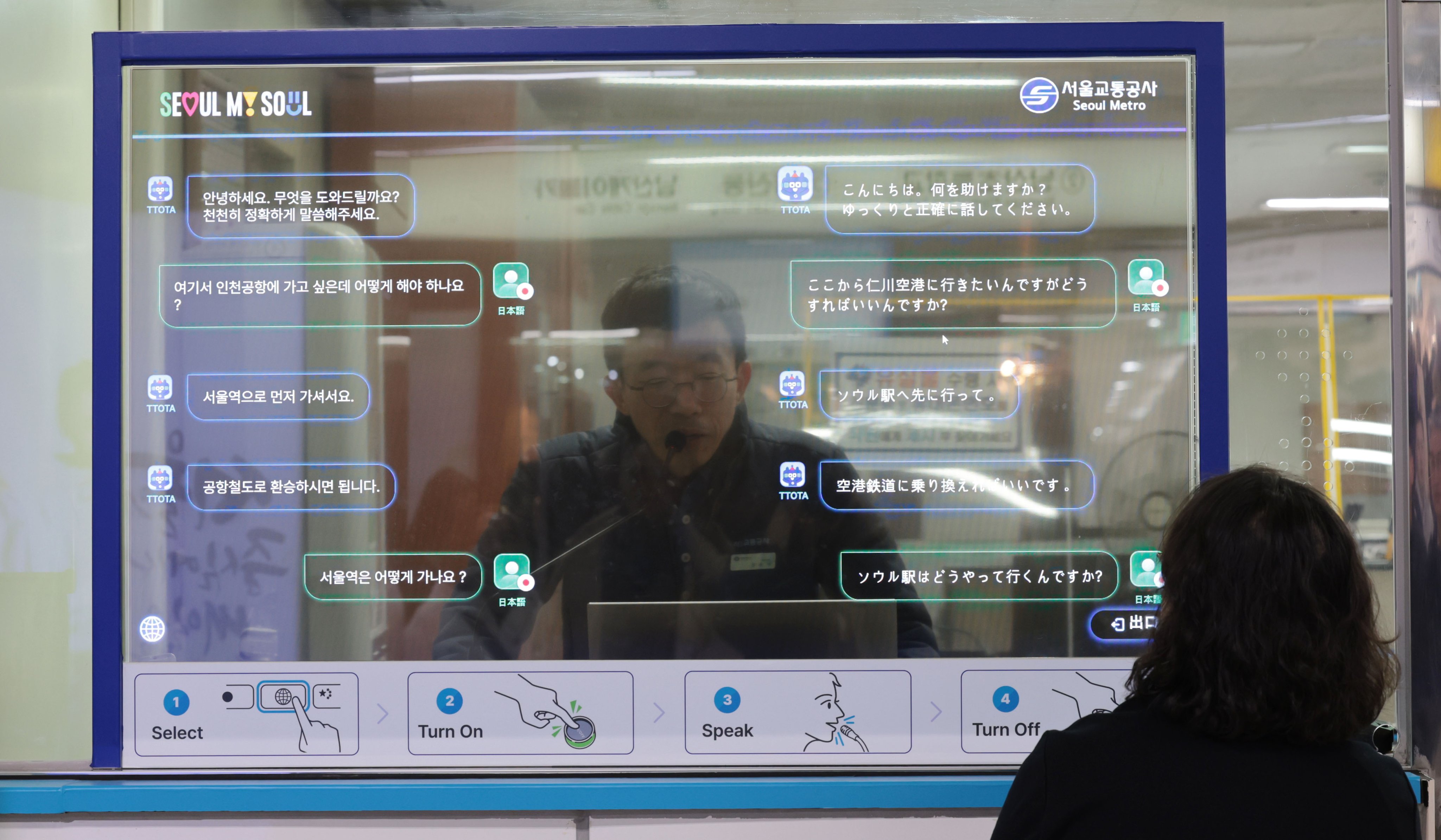 A station employee converses simultaneously with a foreigner in their respective mother tongues through a transparent OLED screen at a subway station in Seoul, South Korea. Photo: EPA-EFE/Yonhap