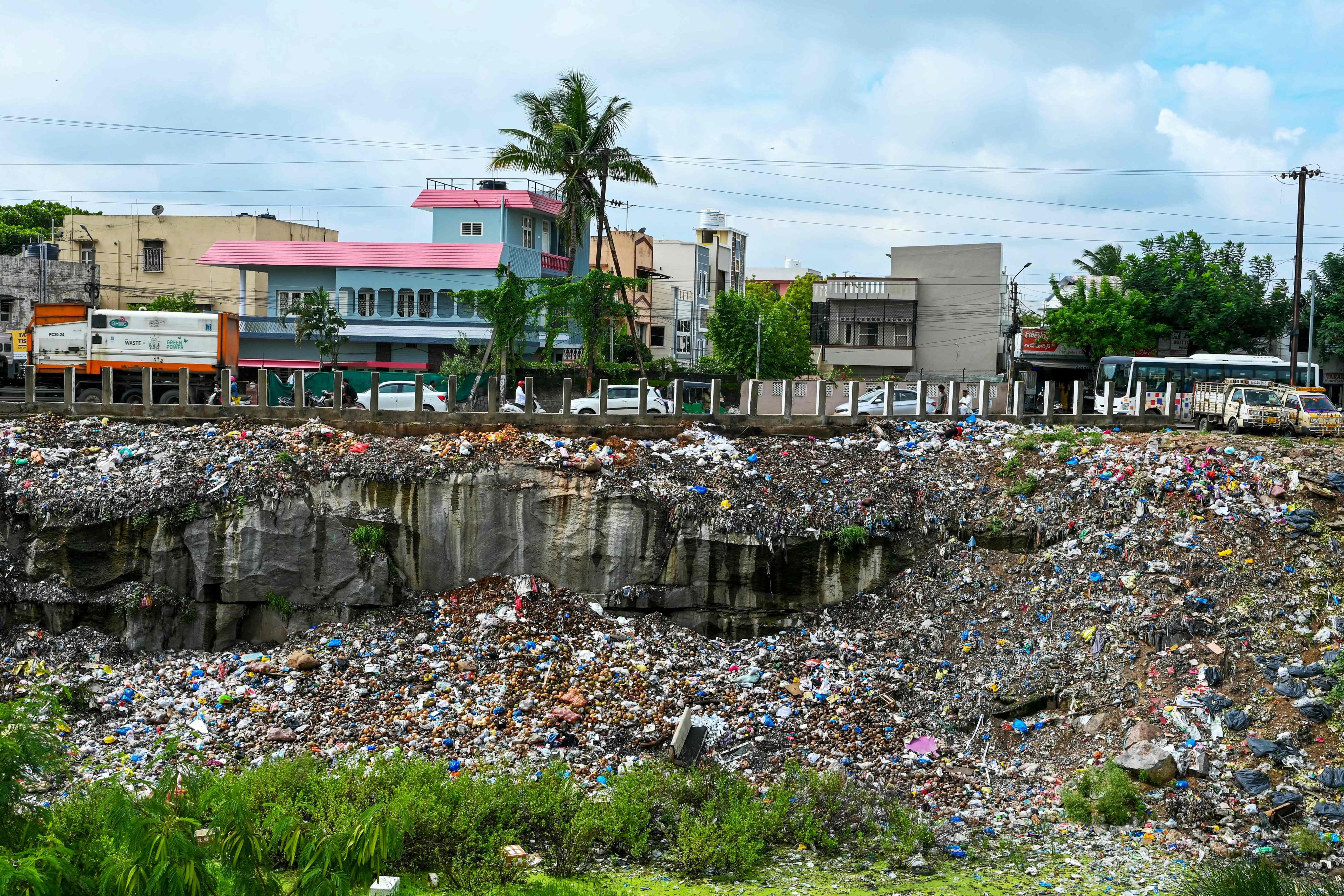 Commuters drive past a pond laden with plastic waste in Hyderabad, India, on Friday. Photo: AFP